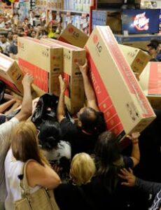 Shoppers crowd together, some holding television boxes above their heads.