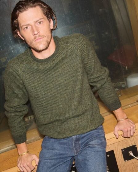 man wearing a green crewneck sweater with jeans