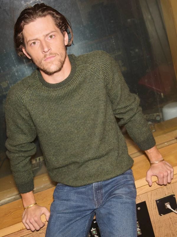 man wearing a green crewneck sweater with jeans