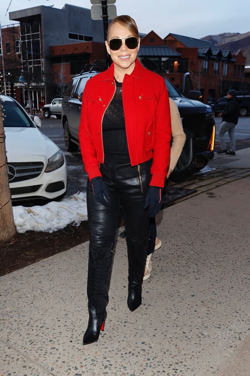 Mariah Carey embraces Christmas Eve shopping at Gucci in Aspen with a festive flair, rocking a chic red cropped jacket over a black sweater, paired with sleek leather pants, pointed-toe stiletto boots, black gloves, and aviator sunglasses for the ultimate winter style.