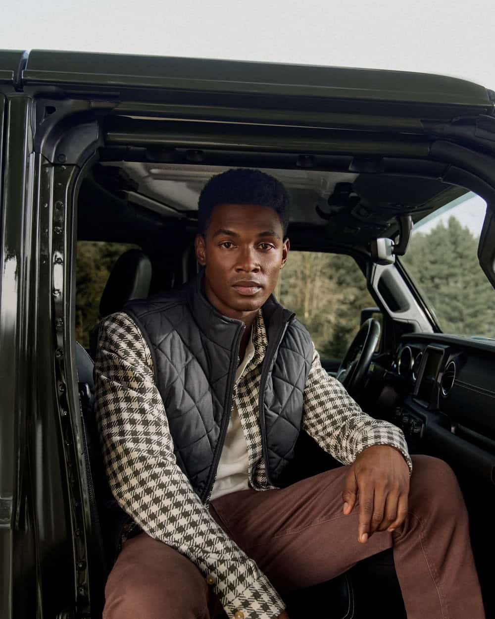 man sitting inside a vehicle wearing a quilted vest