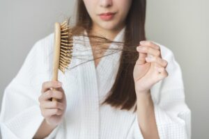 A woman pulling hair from a hairbrush