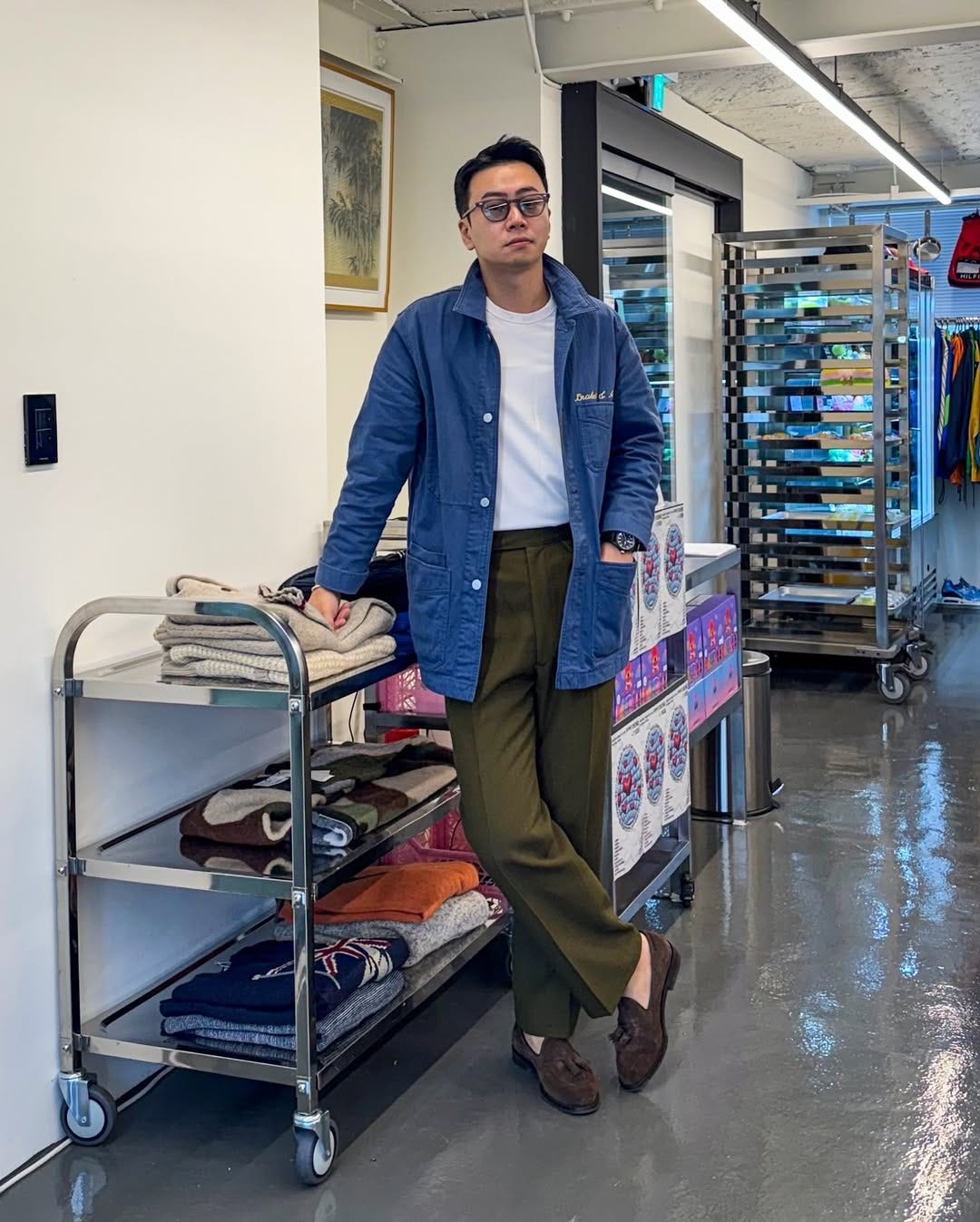 stylish man wearing a blue chore coat, white t-shirt, and olive dress pants