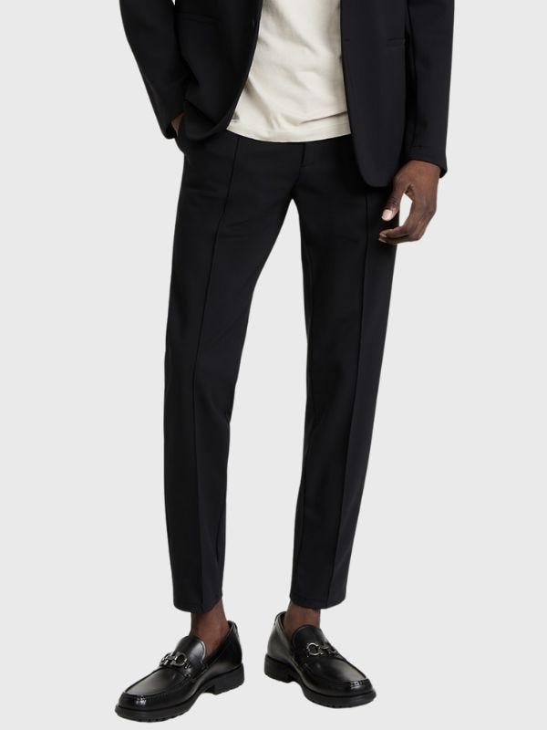 man from the waist down wearing black performance pants and black loafers