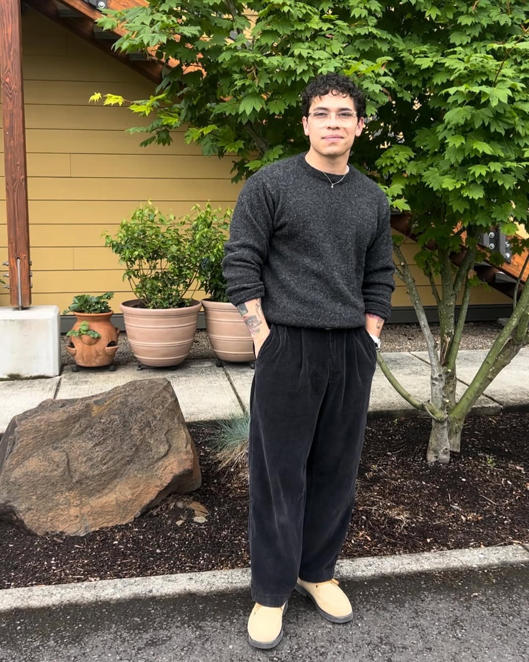 stylish man wearing a grey crewneck sweater with dark grey corduroy pants and tan shoes