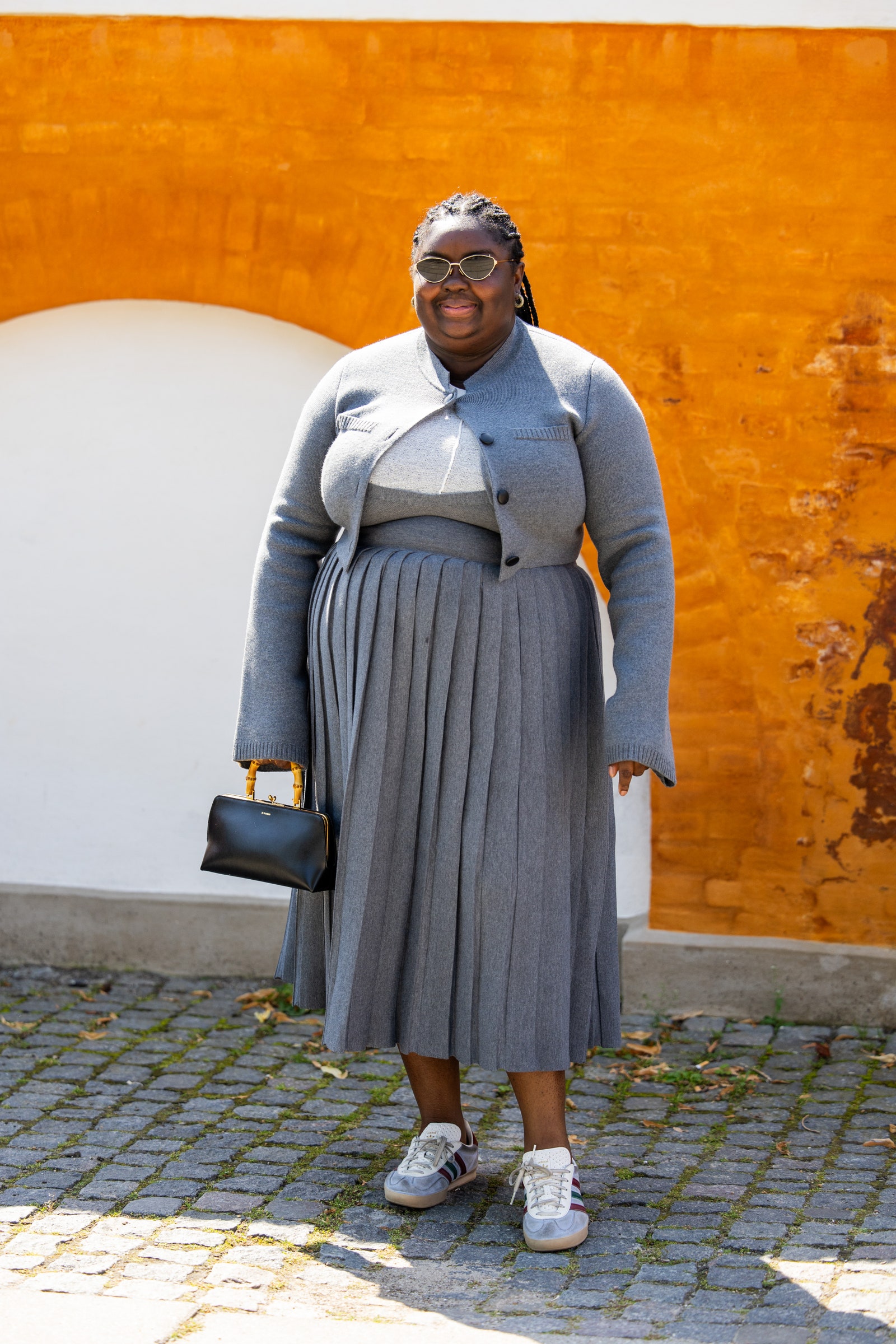 Woman wearing gray cardigan with matching shirt and skirt set and Reebok sneakers