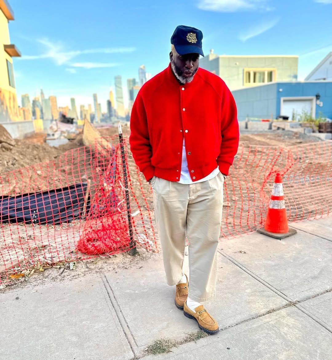 stylish man wearing a bright red jacket over a white t-shirt with tan chinos and suede horsebit loafers