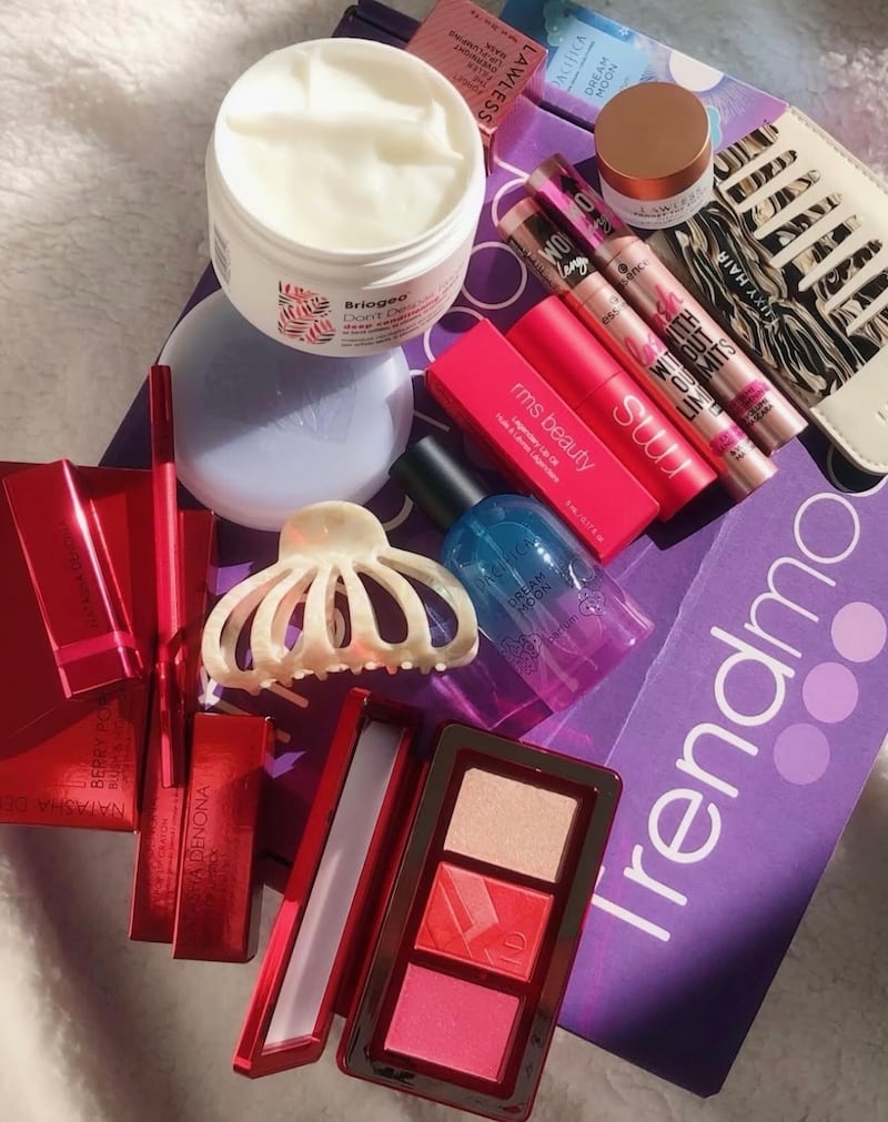 An overhead shot of a Trendmood Box topped with full size products that would be packaged in it, including makeup products from Natasha Denona and haircare from Briogeo.